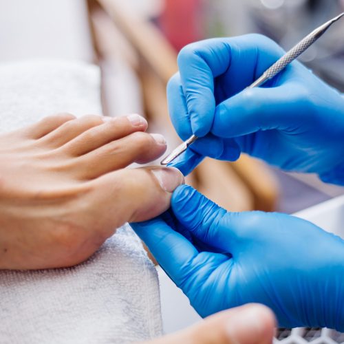 proceso-de-pedicura-pedicura-de-salon-en-casa-tratamiento-de-cuidado-de-los-pies-y-unas-el-proceso-de-pedicura-profesional-maestro-en-guantes-azules-hace-pedicura